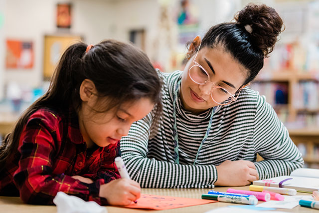 A student teacher coloring with a child